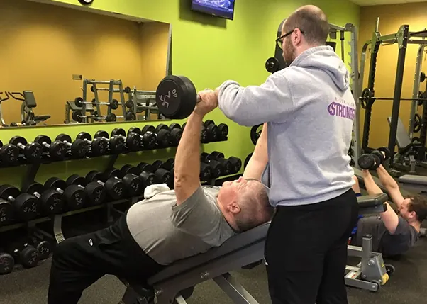 Personal Trainer Helping Stroke Survivor Lifting Weights On a Bench